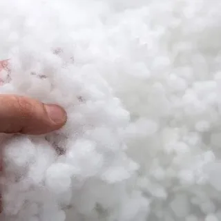 A hand holding loose white polyester staple fiber