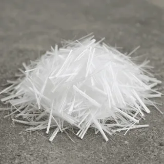 A handful of white polypropylene fibers on a concrete surface before dosing into the mix