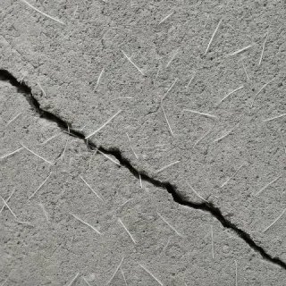 Close-up of a crack in a concrete surface with polypropylene fibers bridging across it